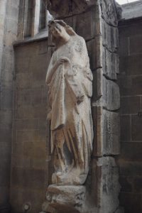 Ein stehender Engel mit schräg geneigtem Kopf steht an einer Säule im Chorraum