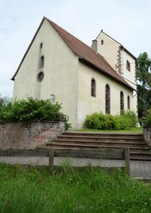 Eine kleine zart-gelbe Kirche mit rotem Dach