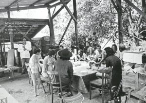 Schwarz weiß Foto von mehreren Personen während sie draußen an einem Tisch sitzen